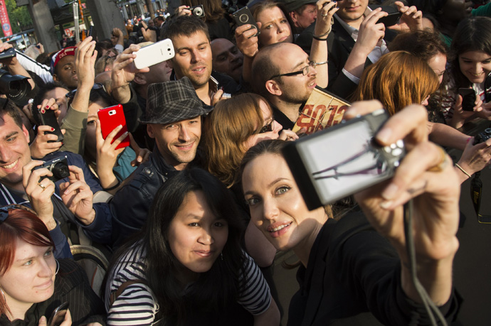 World War Z - Paris Premiere - Red Carpet ArrivalsPARIS, FRANCE - JUNE 03:  Angelina Jolie takes a photo of herself with a fan's camera as she poses with fans upon her arrival for the Paris premiere of "World War Z" at Cinema UGC Normandie on June 3, 2013 